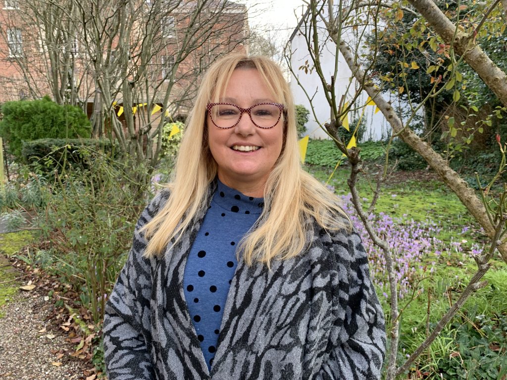 A photo of Sharon Blythe with long blonde hair and glasses and a big smile